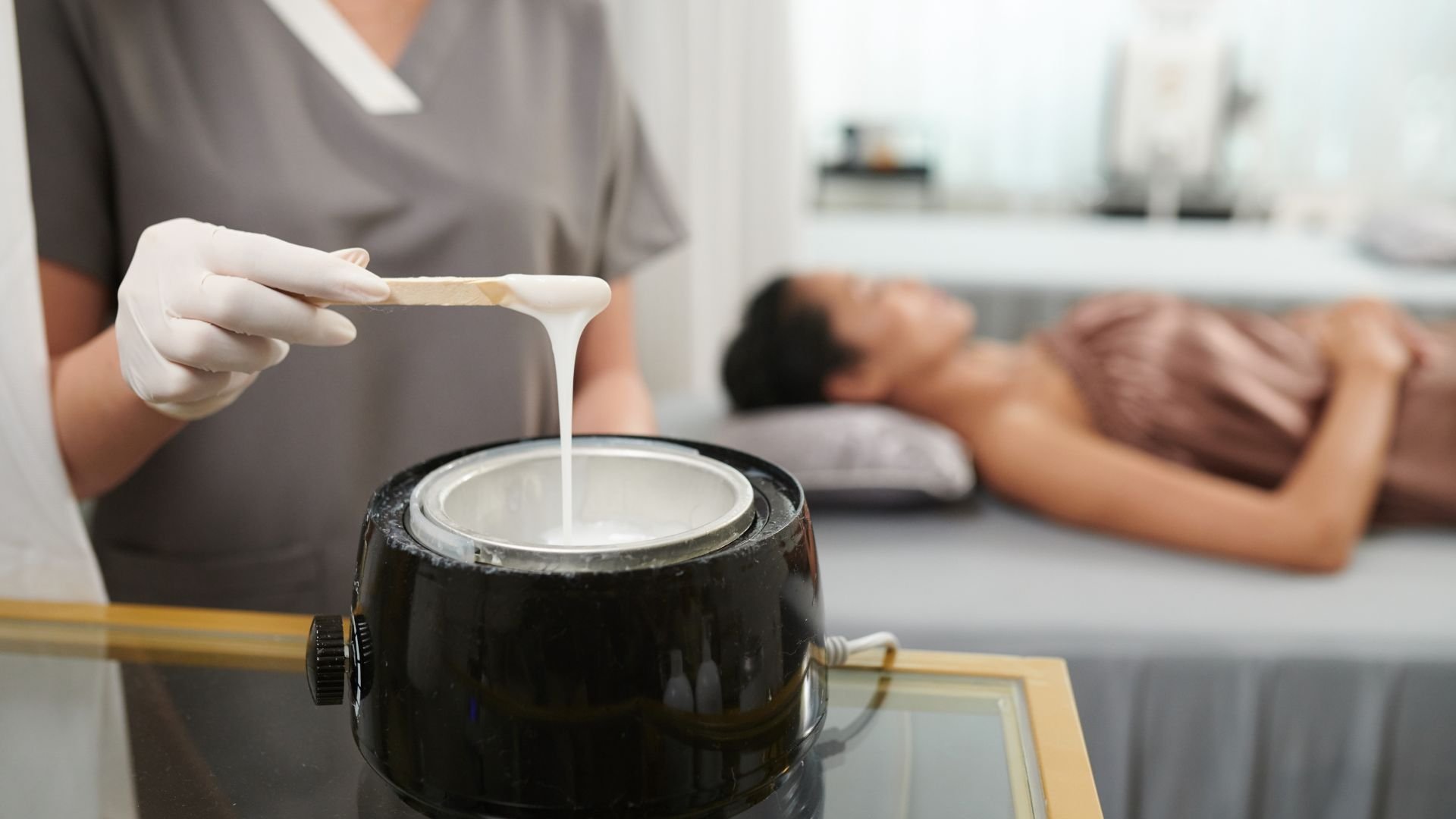 Esthetician applying hot wax for hair removal treatment