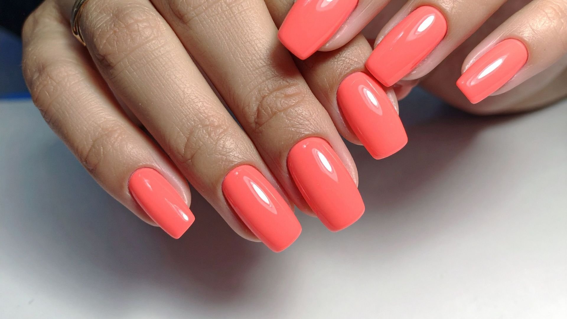 Glossy coral pink manicure on long, square-shaped nails