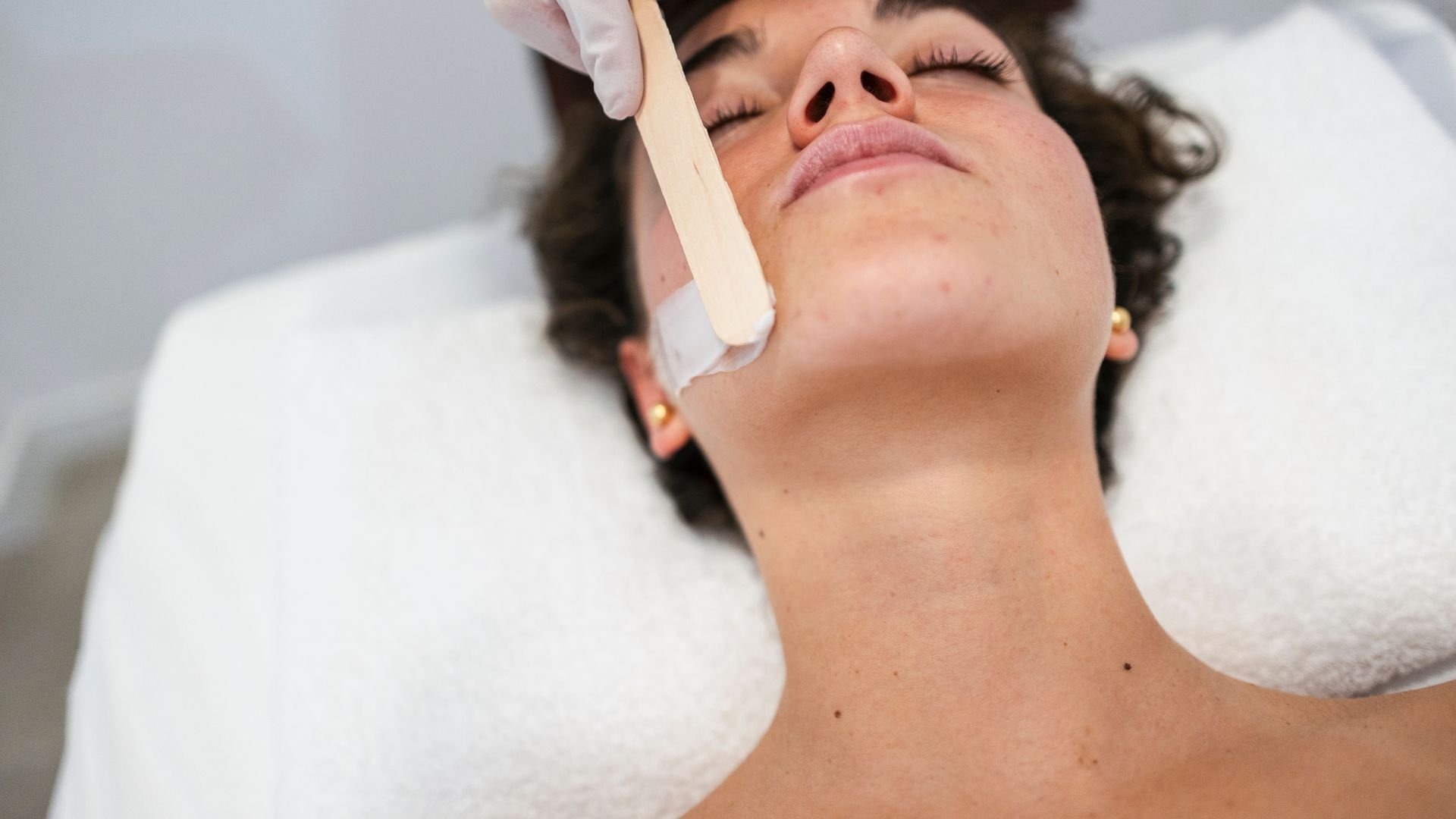 Facial hair removal treatment with wax strip on person's chin